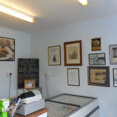 Photo of Baxter's fish shop interior showing the cash till, the serving counter, a chalk board listing items for sale and various photos on the wall.