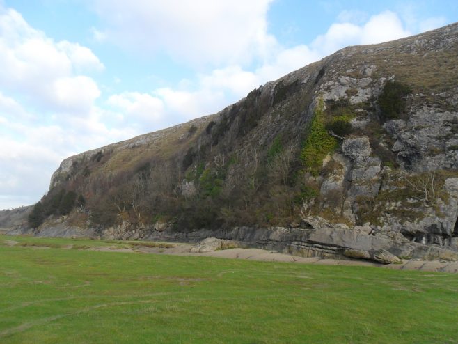 View of cliff at Humphrey Head and grassy area on beach.