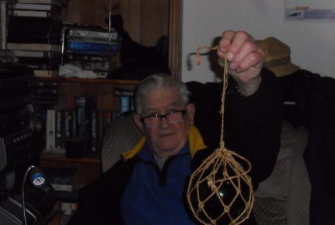 Ernie Nicholson holding up a glass fishing float in netting.