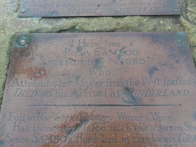 Close-up of top half of plaque on Sambo's Grave at Sunderland Point showing some of the lettering on the grave marker.