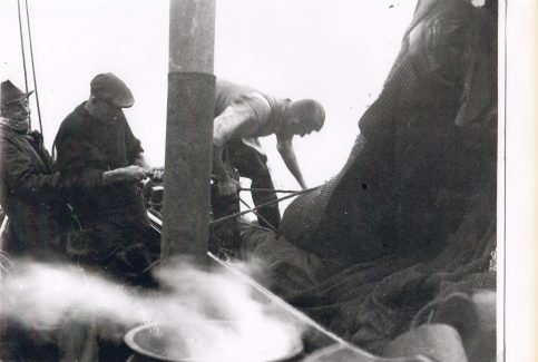 Aboard a shrimp boat, the crew tend to their net. The steam is from a boiler used for boiling shrimps at sea